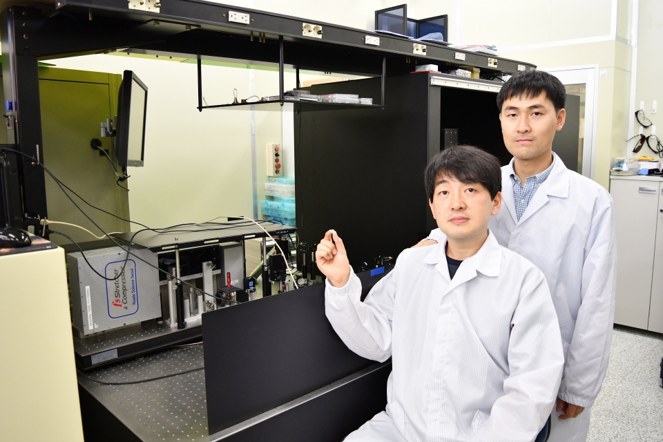 연구개발자인 정보수 선임(앞)과 이병학 선임이 펨토초 레이저 장비 앞에서 표면처리 된 티타늄을 들고 포즈를 취하고 있다. (사진=KERI)