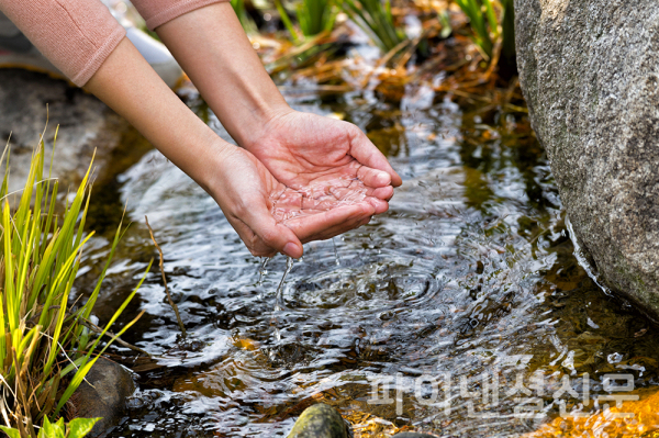 삼성전자 직원이 화성 사업장 ‘그린센터(폐수처리시설)’에서 정화시킨 물로 조성한 연못에서 손을 적시는 모습. (사진=삼성전자)