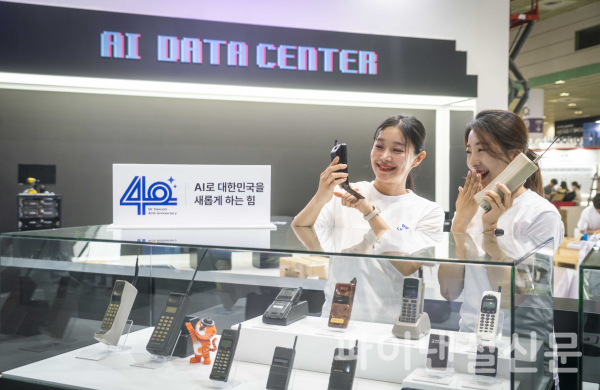 모델들이 '월드 IT 쇼(WIS) 2024' SKT 전시관에 전시된 다양한 형태의 과거 이동전화를 살펴보고 있다. (사진=SKT)