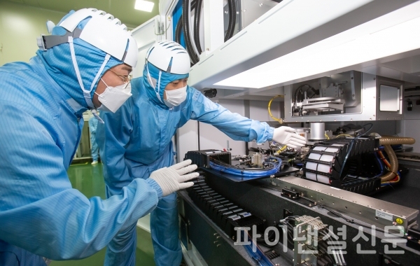 삼성전자 직원(좌)과 이오테크닉스 직원(우)이 양사가 공동 개발한 반도체 레이저 설비를 함께 살펴보고 있다./사진=삼성전자