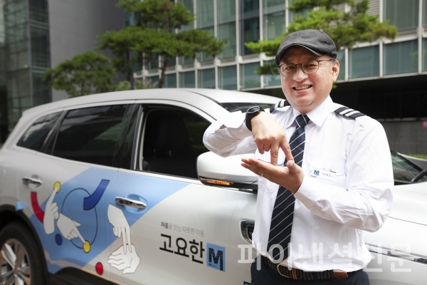 청각장애인 기사님이 수어 아티스트 '지후트리'가 '자립'이라는 수어를 이미지화해 디자인한 '고요한M' 차량 앞에서 수어로 '자립'을 표현하고 있는 모습. (사진=SK텔레콤)